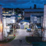 Power plant facility with illuminated towers during evening operations.