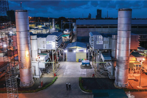 Power plant facility with illuminated towers during evening operations.