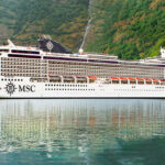 MSC cruise ship docked near lush coastal cliffs