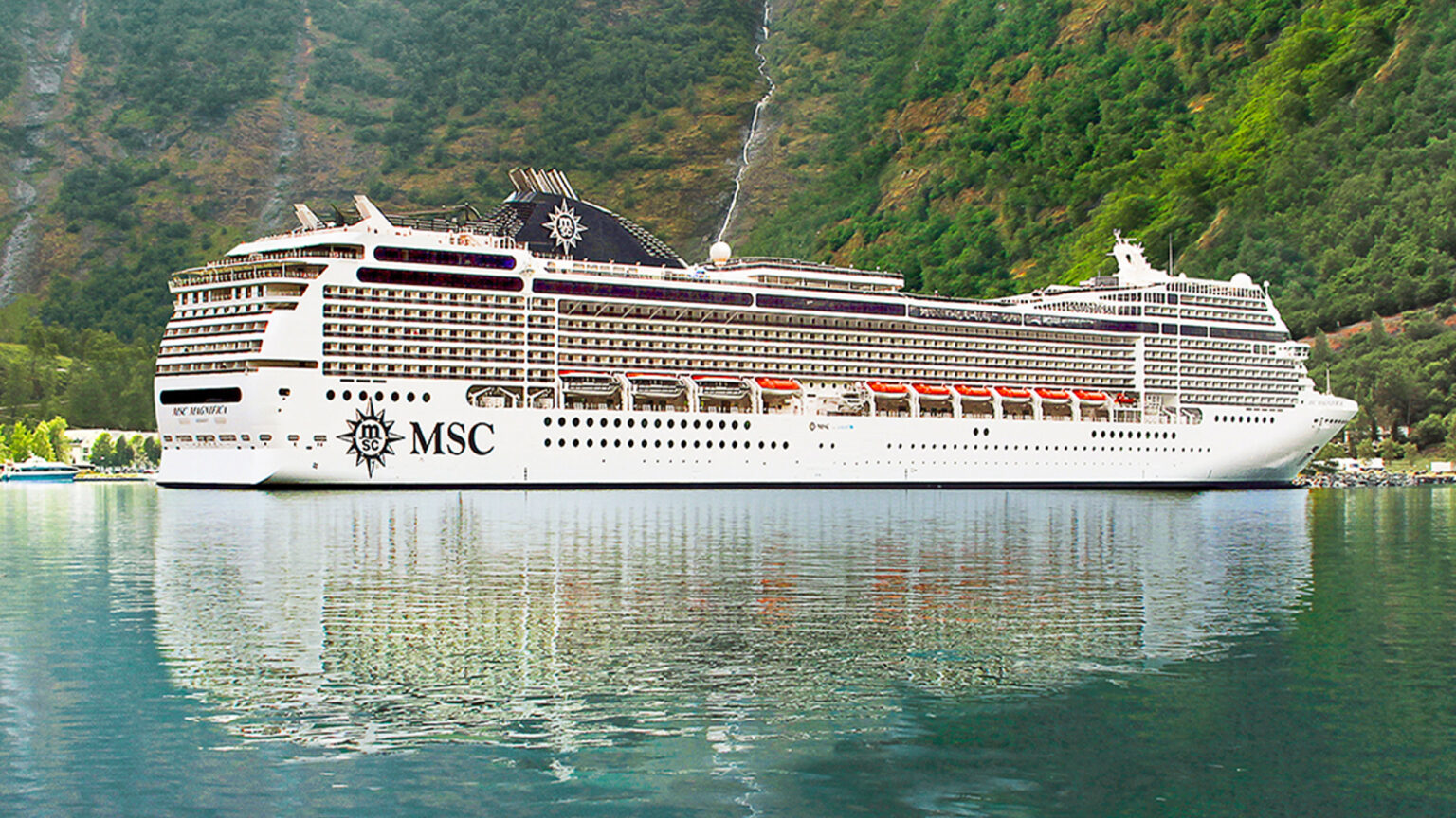 MSC cruise ship docked near lush coastal cliffs