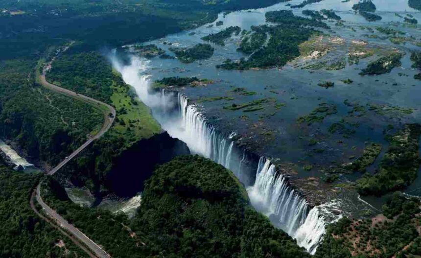 Aerial view of Victoria Falls on the Zambezi River, showcasing the vast gorge and surrounding greenery between Zimbabwe and Zambia