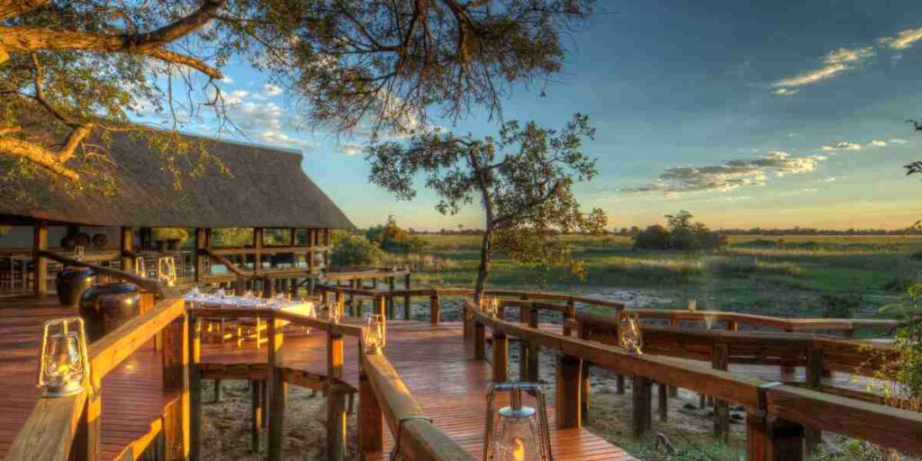 Outdoor deck at a luxury safari lodge in Botswana’s Okavango Delta overlooking floodplains at sunset.