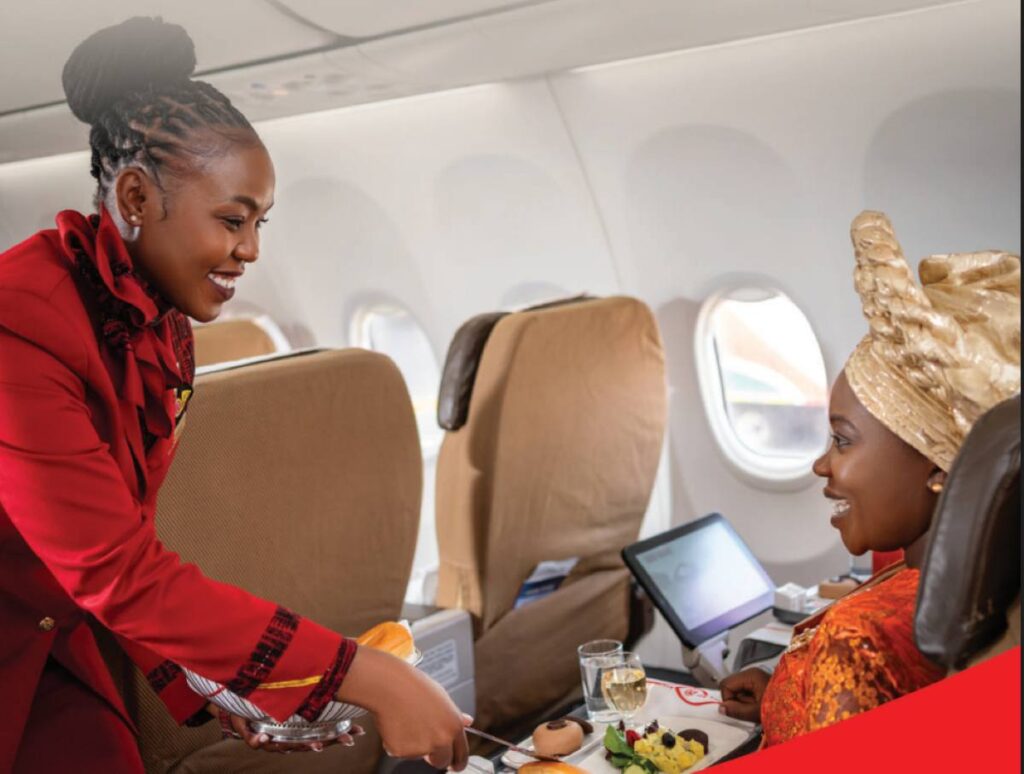 Kenya Airways flight attendant attending to a passenger during flight.
