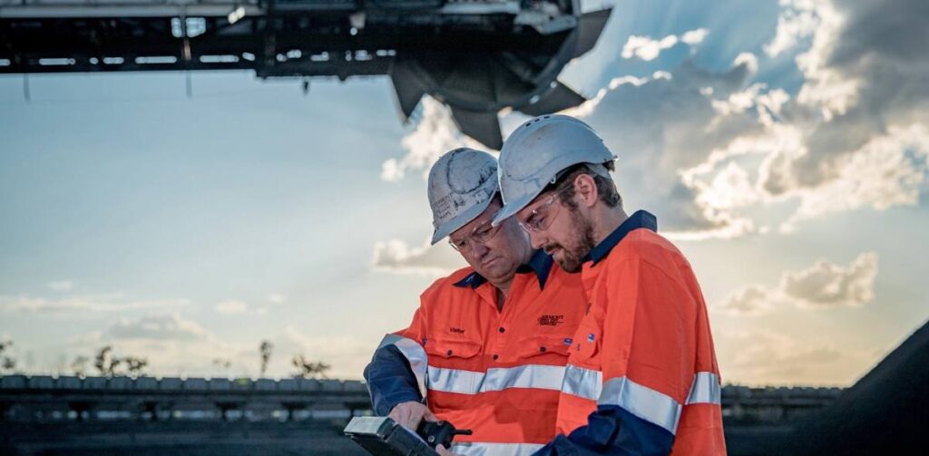 Workers at Glencore coal mining operation managing extraction and processing activities in an industrial site.